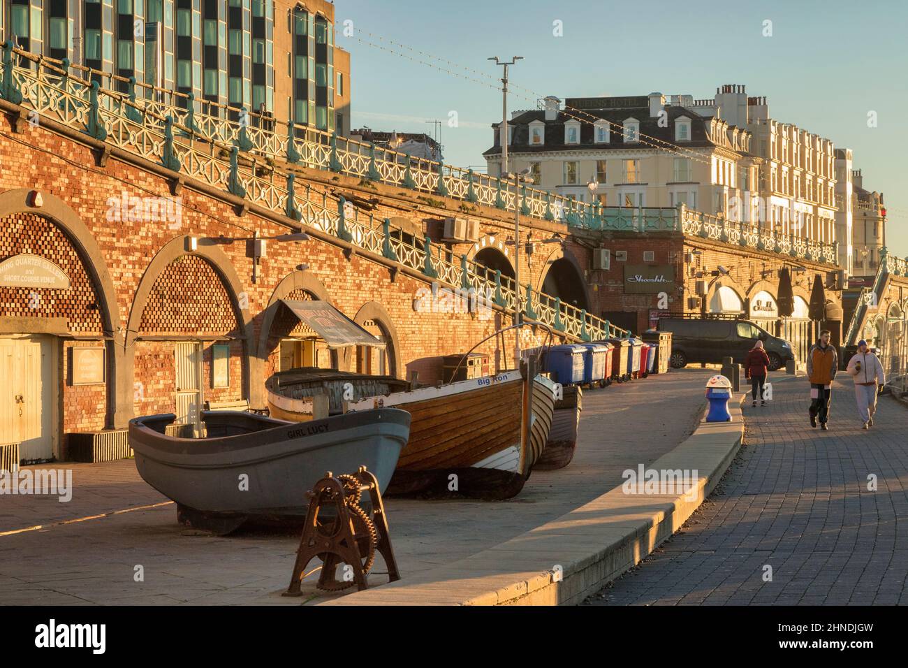 14. Januar 2022: Brighton, East Sussex, Großbritannien - Paar läuft an Booten vorbei, am frühen Wintermorgen auf der Brighton Promenade, East Sussex, Großbritannien Stockfoto