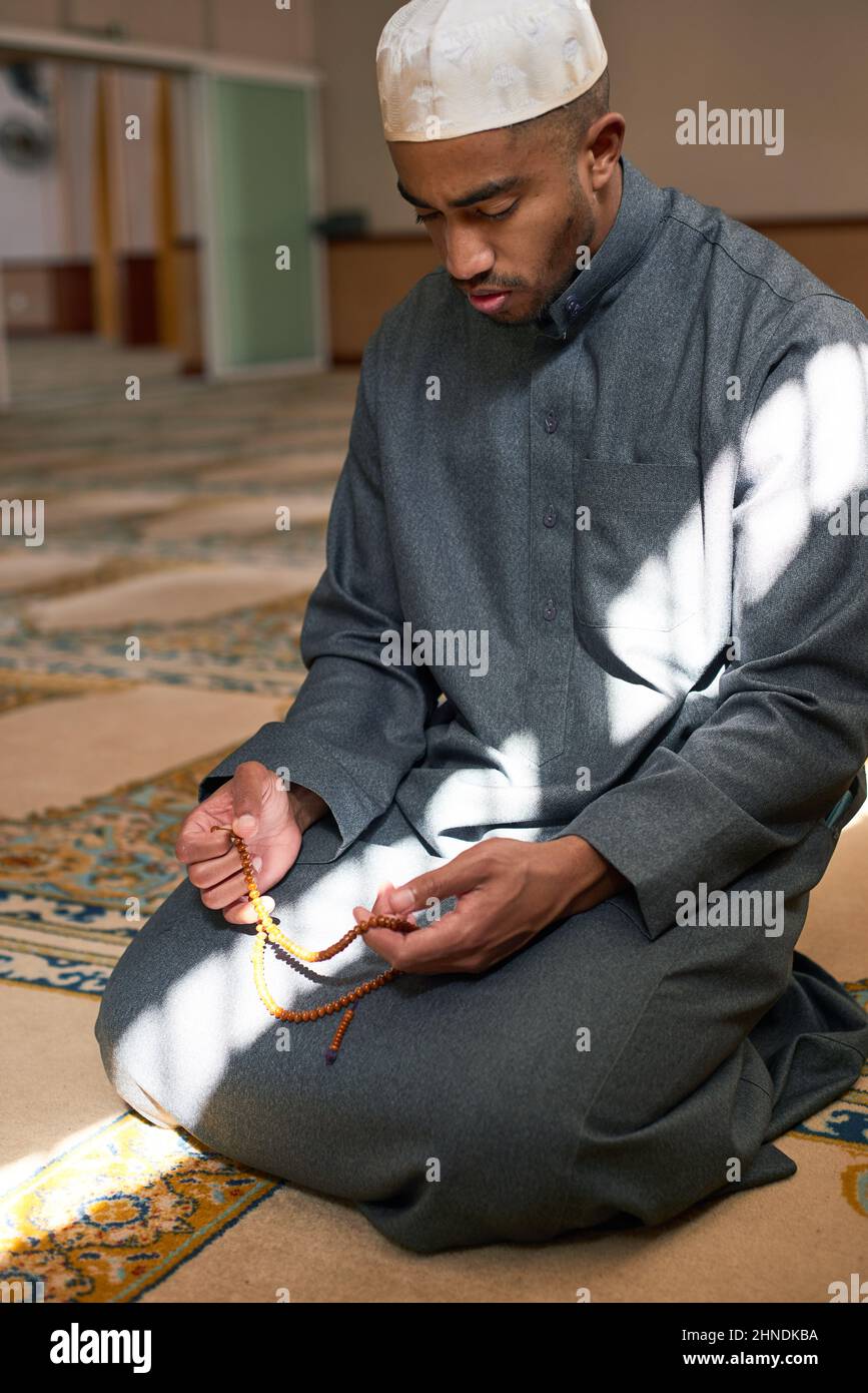 Porträt eines Mannes auf den Knien mit Gebetsperlen in einer Moschee Stockfoto