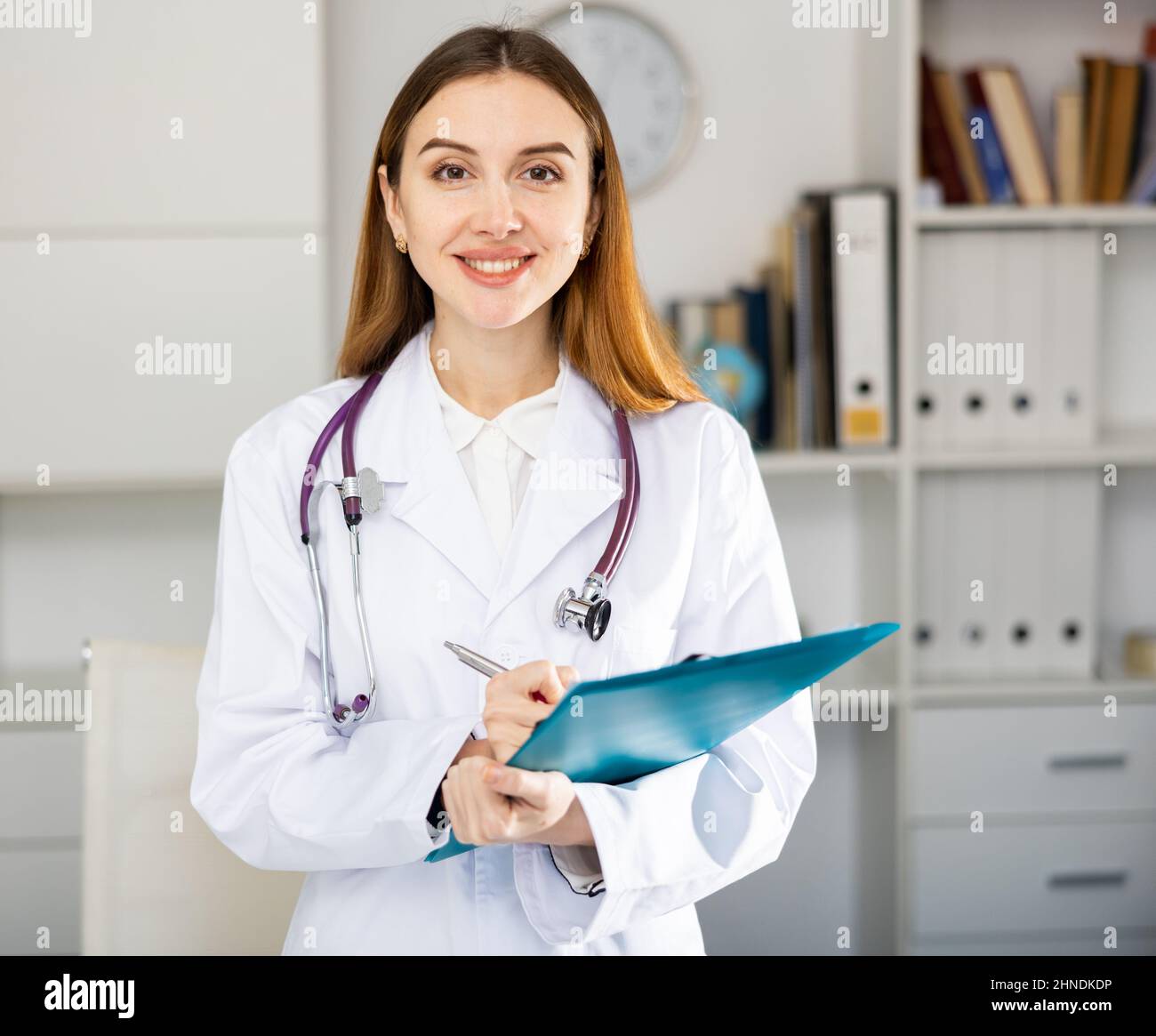 Krankenschwester steht im medizinischen Büro mit Klemmbrett Stockfoto