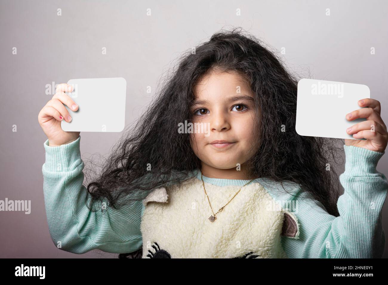 Kleines Mädchen Porträt hält zwei Flash-Karte in den Händen, Vorschulkinder Bildungsmaterial Lernobjekte . Flash-Karten Auswahlpfad enthalten. Stockfoto