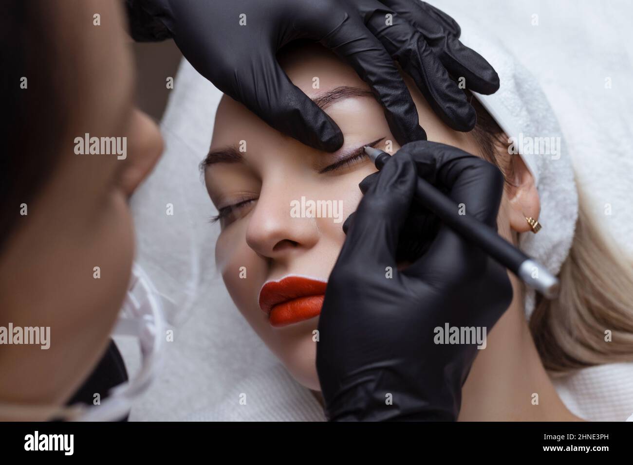 Dauerhaftes Make-up. Kosmetologe Tattoo Künstler wendet eine Kontur auf das Augenlid des Kunden für die anschließende Anwendung der Augen Tätowierung Stockfoto