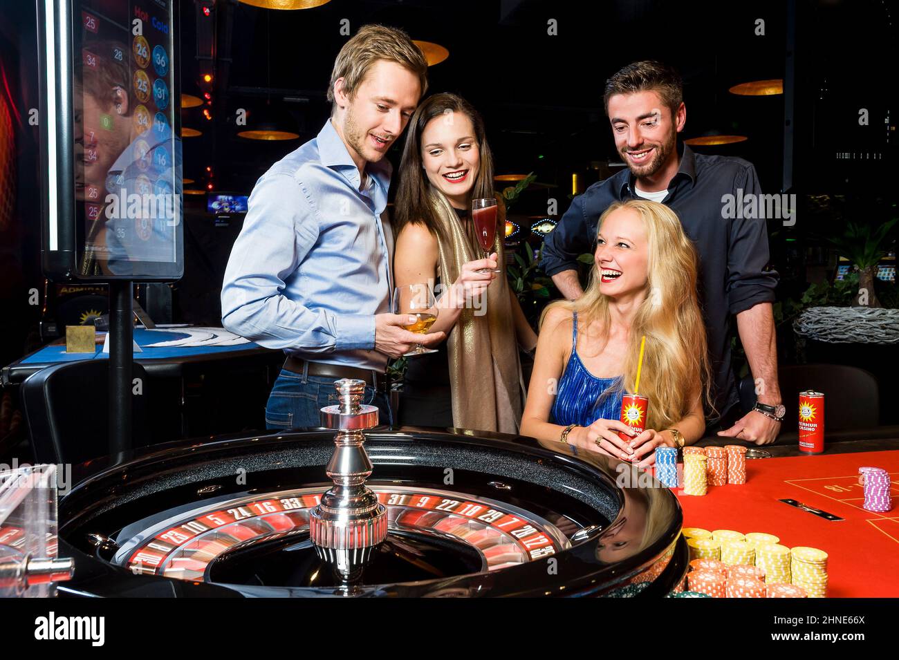 Gruppe von jungen Menschen mit Fan mit Roulette im Casino Stockfoto