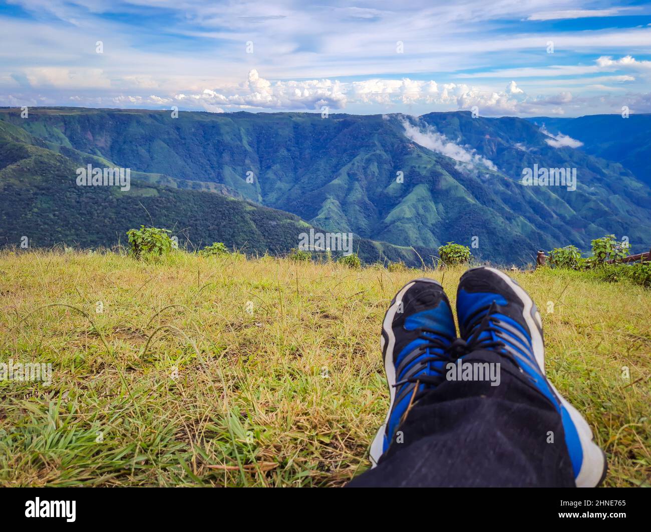 Alleinreisende Füße auf Berggipfel mit hellblauem Himmel am Morgen Stockfoto
