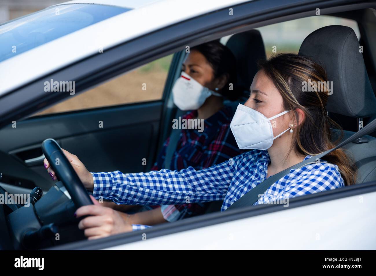 Zwei Frauen in Schutzmasken im Innenraum eines Autos Stockfoto
