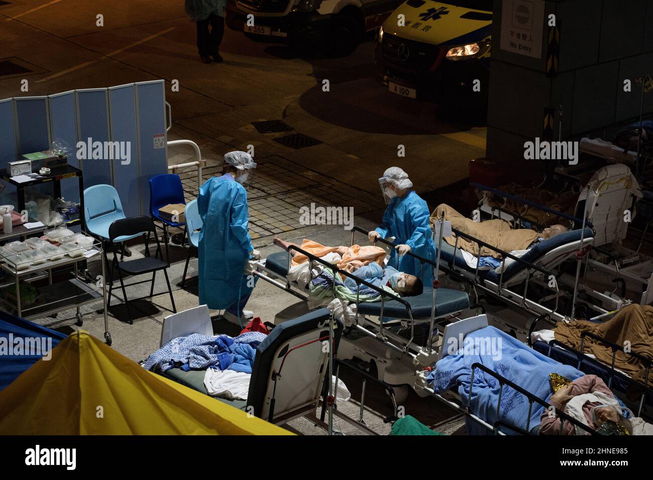 Gesundheitsfachkräfte, die persönliche Schutzanzüge (PSA) tragen, nehmen an covid-19 Patienten auf ihren Betten Teil. Hongkong kämpft darum, den Ausbruch von Covid-19 einzudämmen, wobei die meisten Krankenhäuser über ihre Kapazitäten verfügen. Patienten auf Krankenhausbetten standen vor Den A&E-Abteilungen des medizinischen Zentrums der Caritas und warteten darauf, ins Krankenhaus zu kommen. (Foto von Dominic Chiu / SOPA Images/Sipa USA) Stockfoto