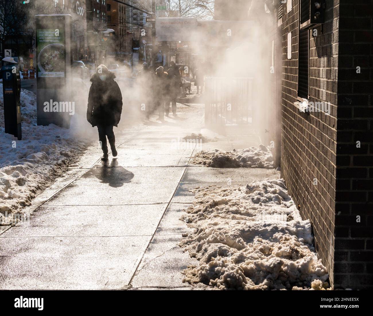 Fußgänger auf gerodeten Gehwegen passieren am Sonntag, dem 30. Januar 2022, in Chelsea in New York einen belüfteten Dampf, nachdem ein Nor-Oster-Wasserdruck von 8 cm in der Stadt stattfand und das kalte Wetter den Schnee eingefroren hatte. (© Richard B. Levine) Stockfoto