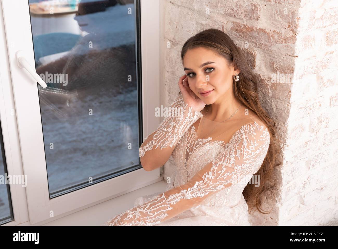 Braut mit fließendem Haar auf der Fensterbank. Hochwertige Fotos Stockfoto