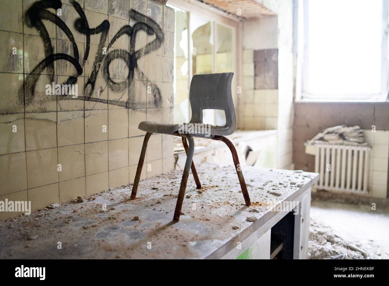 Staubiger und zerstörter Kinderstuhl in der alten staubigen Küche eines verlassenen Sanatoriums, Deutschland Stockfoto