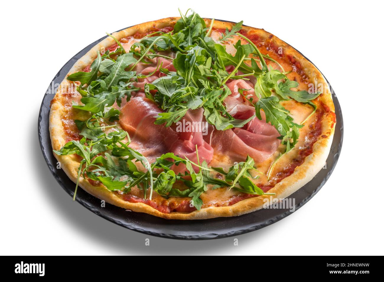 Pizza mit parmaschinken, Tomatensauce und Rucola auf schwarzem Teller isoliert auf weißem, schneidendem Pfad Stockfoto