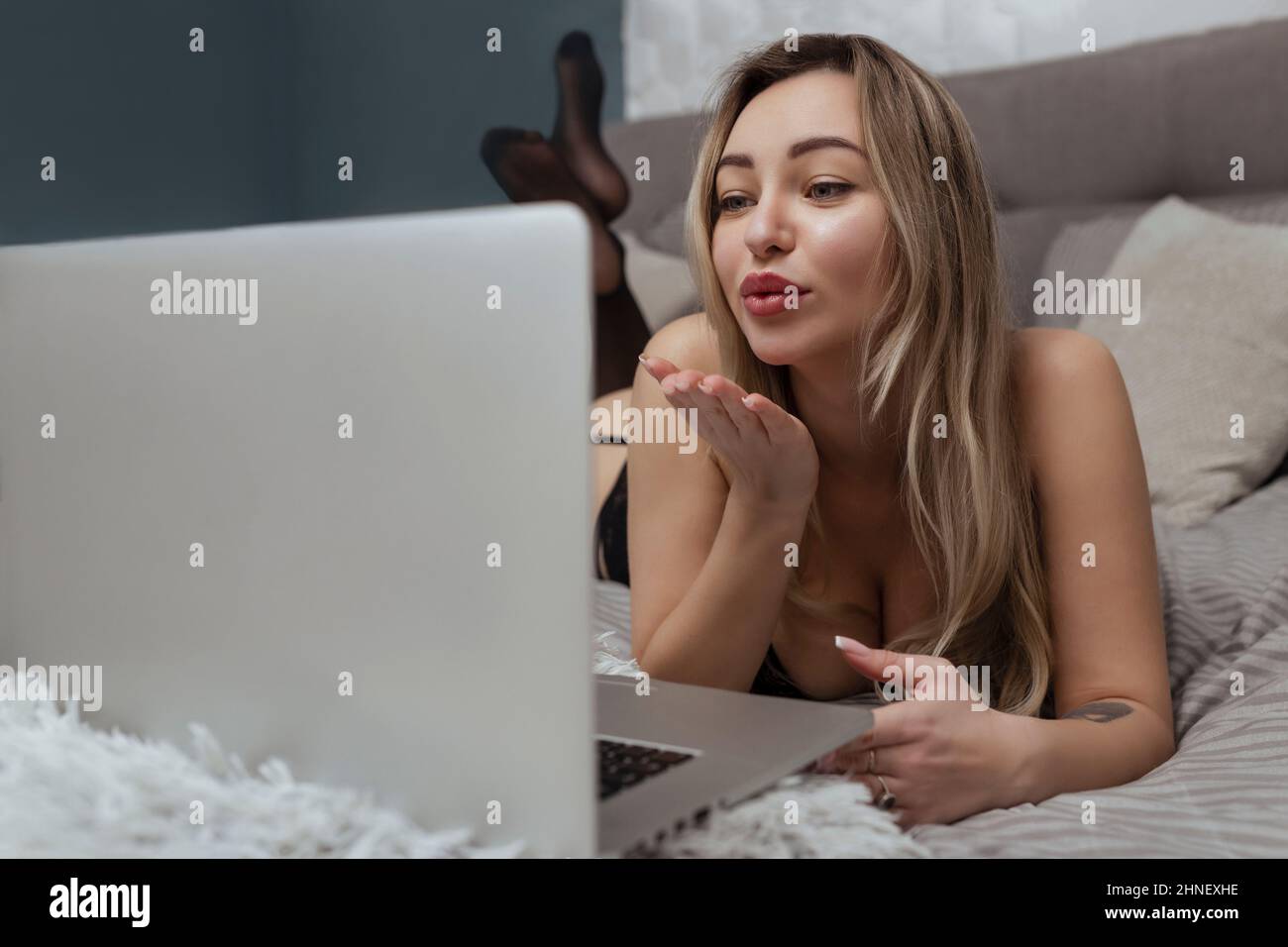 Ein schönes, junges Mädchen schießt eine Webcam, wirft einen Kuss in die Kamera, arbeitet als Model. Das Konzept des Online-Flirts, Sex im Internet Stockfoto