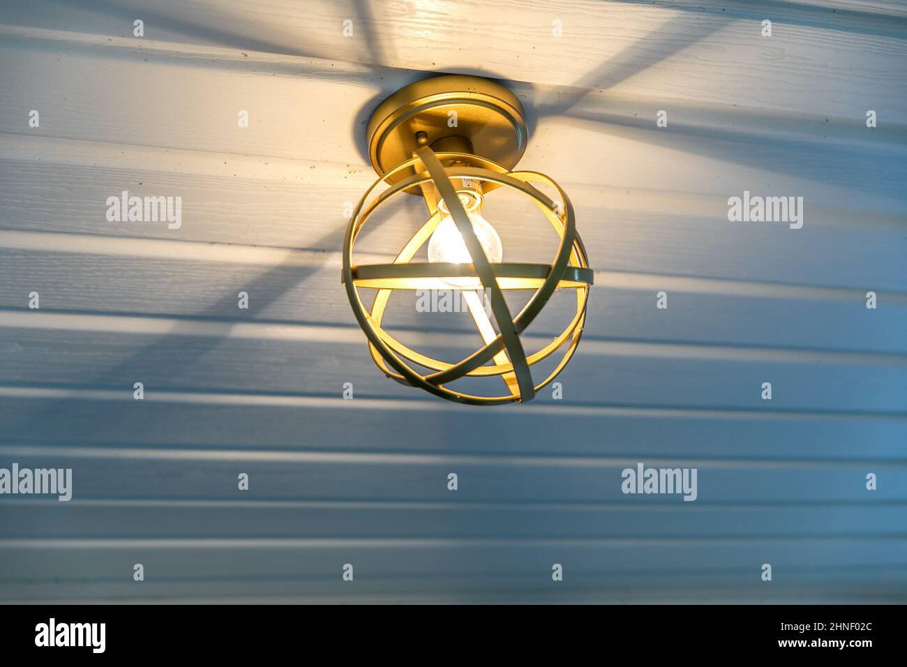 Außenbeleuchtung in Retro-Gold an einer Veranda-Decke Stockfoto