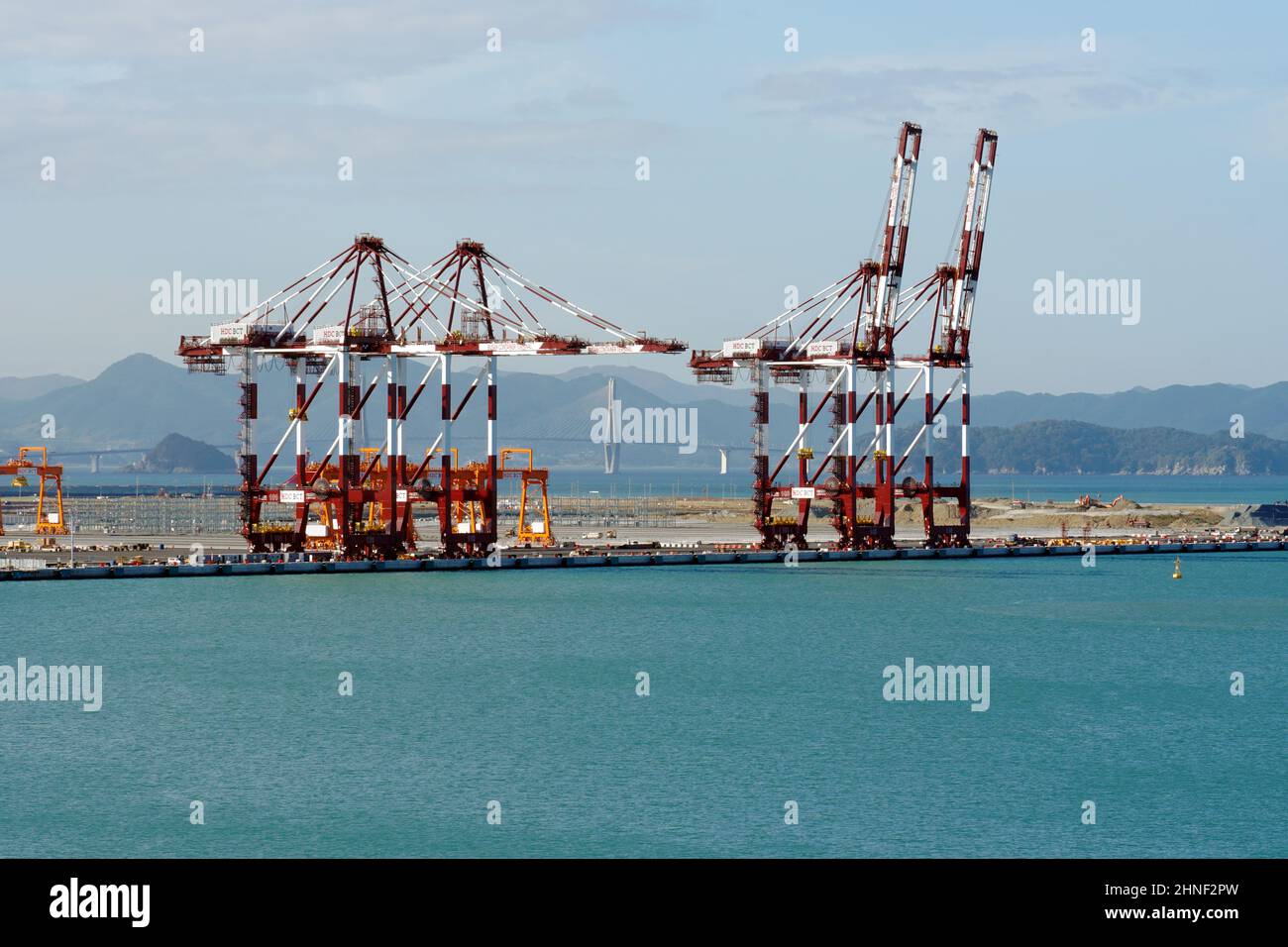 Rote Portalkrane mit weißen Streifen im Containerterminal im Bau in Busan New Port. Stockfoto