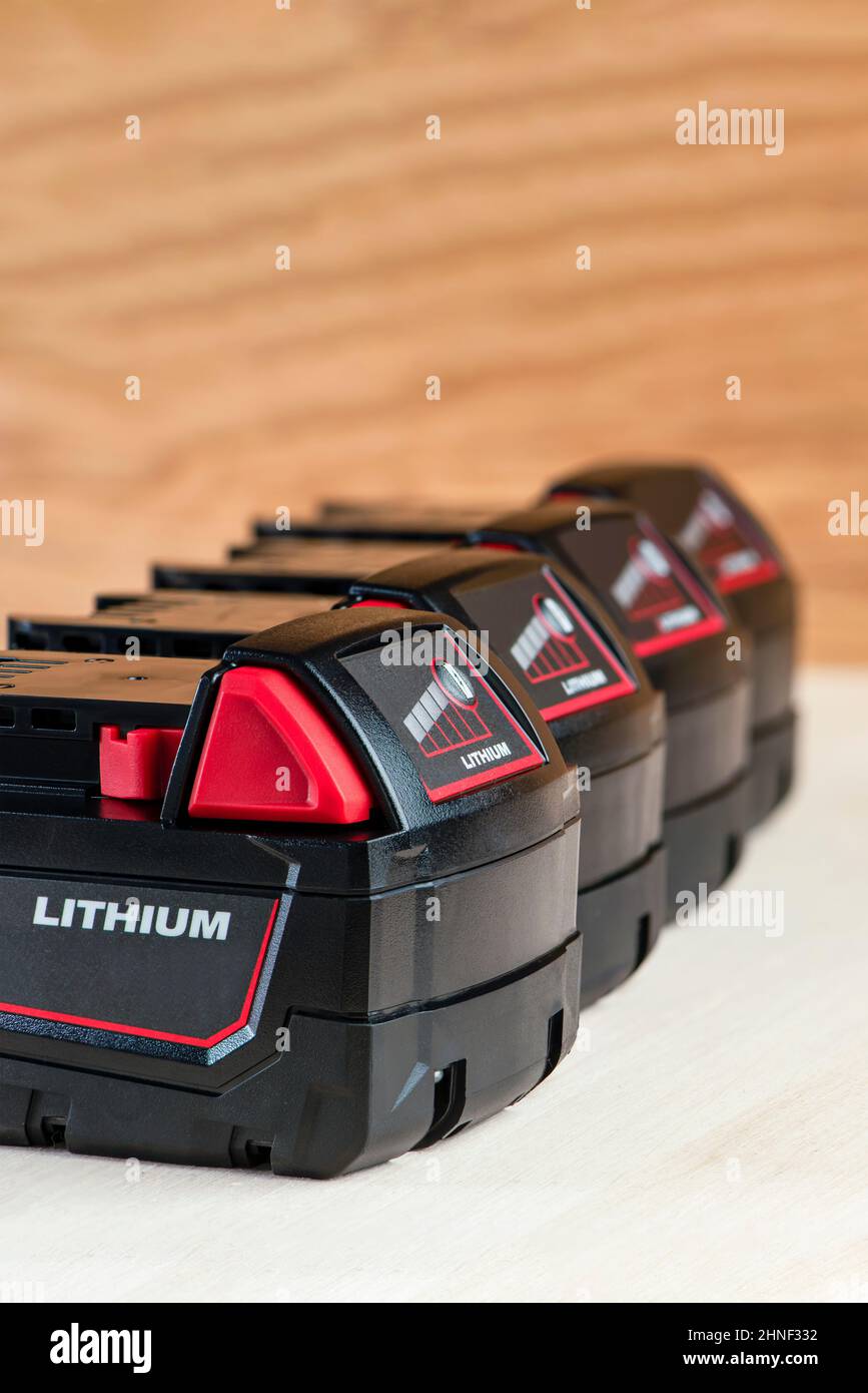 Akku für Akku-Bohrmaschine. Schrauberbatterie. Vier Batterien mit Ladeanzeige liegen auf einem Holzhintergrund Stockfoto