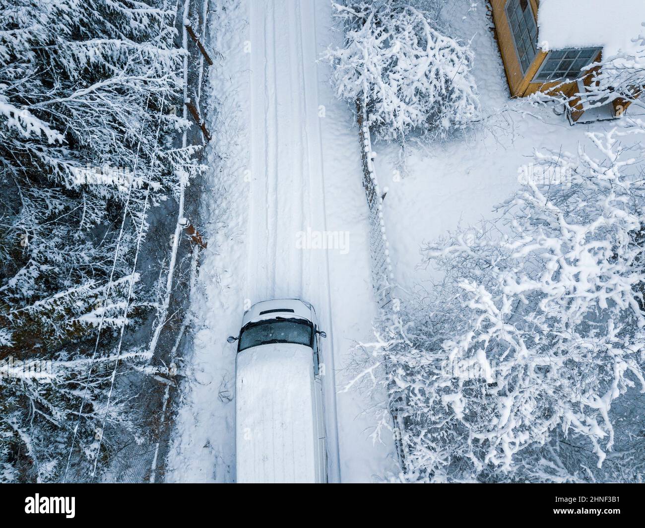 Ein Minivan, der auf einer leeren, schneebedeckten Straße fährt, Luftaufnahme Stockfoto