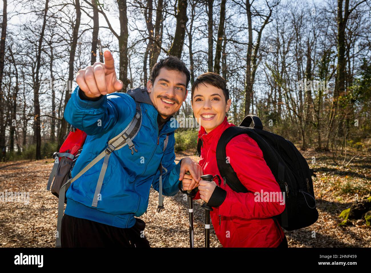 Ein junges lächelndes Paar wandert im Wald. Der Mann weist seiner Freundin den richtigen Weg. Reise- und Outdoor-Life-Konzept Stockfoto