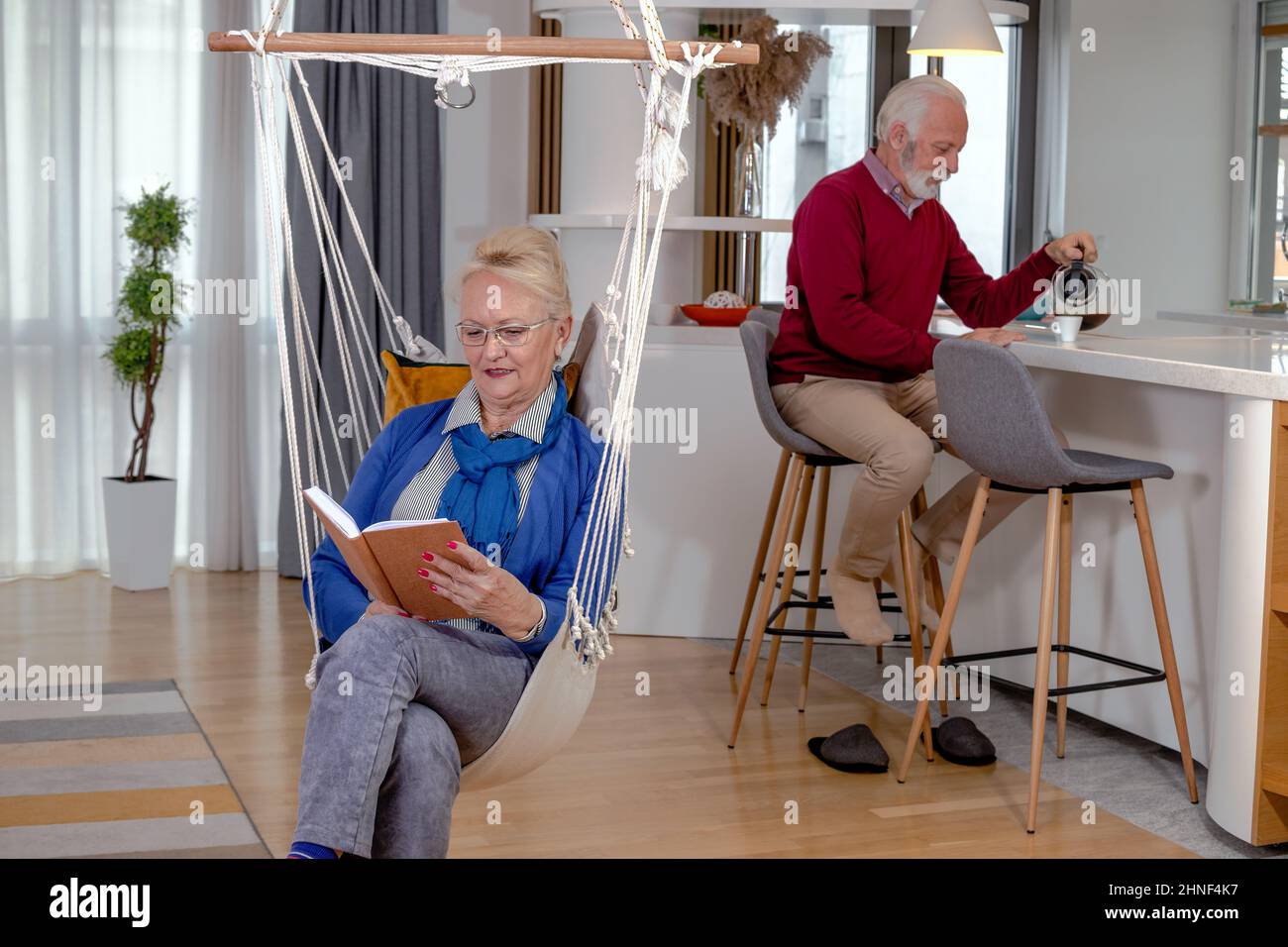 Schönes Seniorenpaar, das sich Zeit genommen hat, sich ausruhte, Kaffee getrunken und zu Hause gelesen hat. Stockfoto
