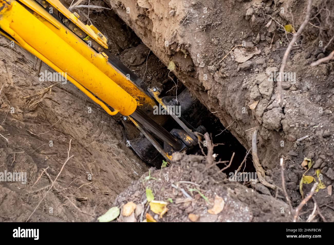 Ein Bagger mit einem langen Ausleger gräbt einen Kanalisationsbrunnen. Bau einer Klärgrube auf dem Land. Stockfoto