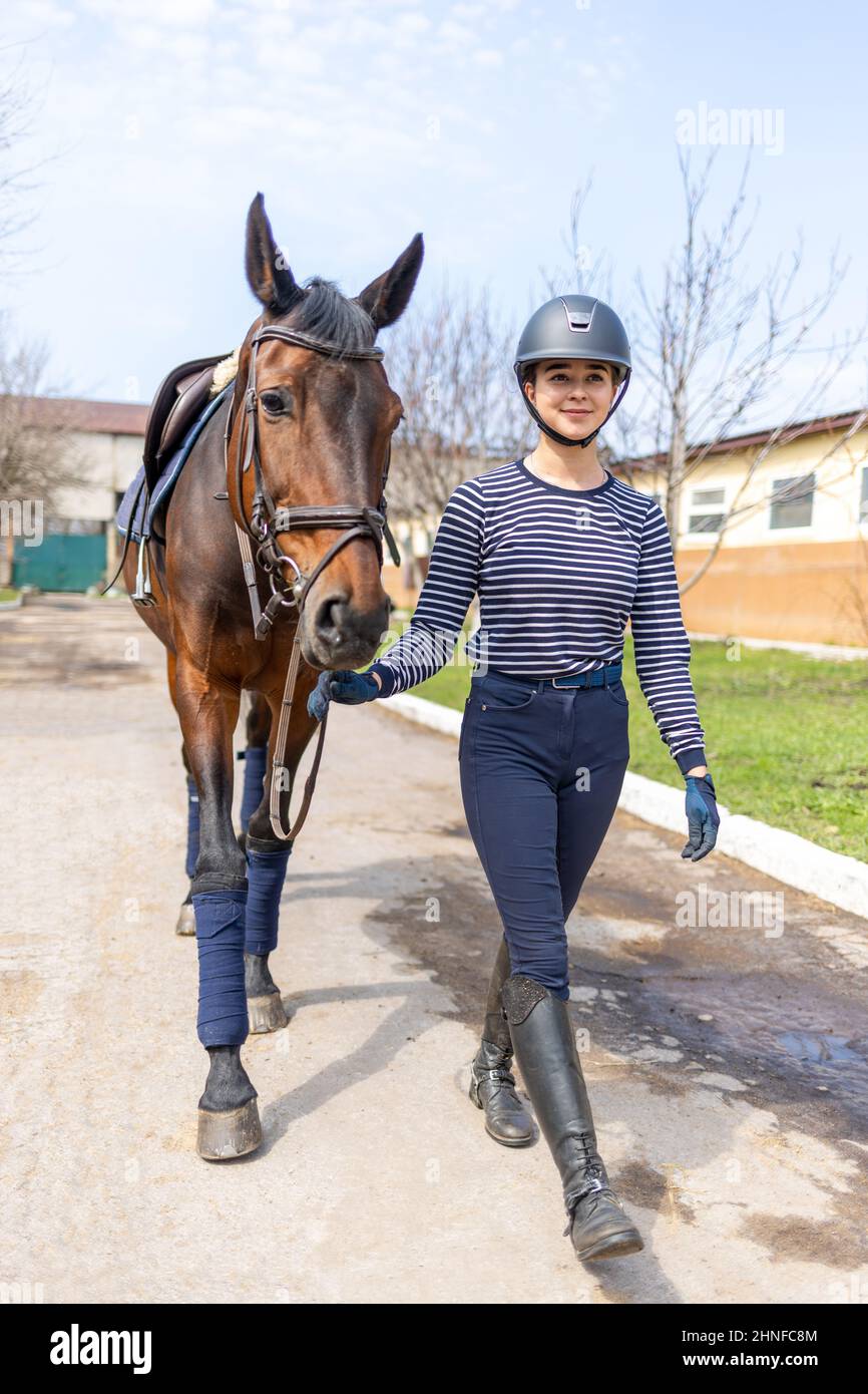 Junge Jockey teen Mädchen zu Fuß mit dem Pferd vor dem Training Stockfoto