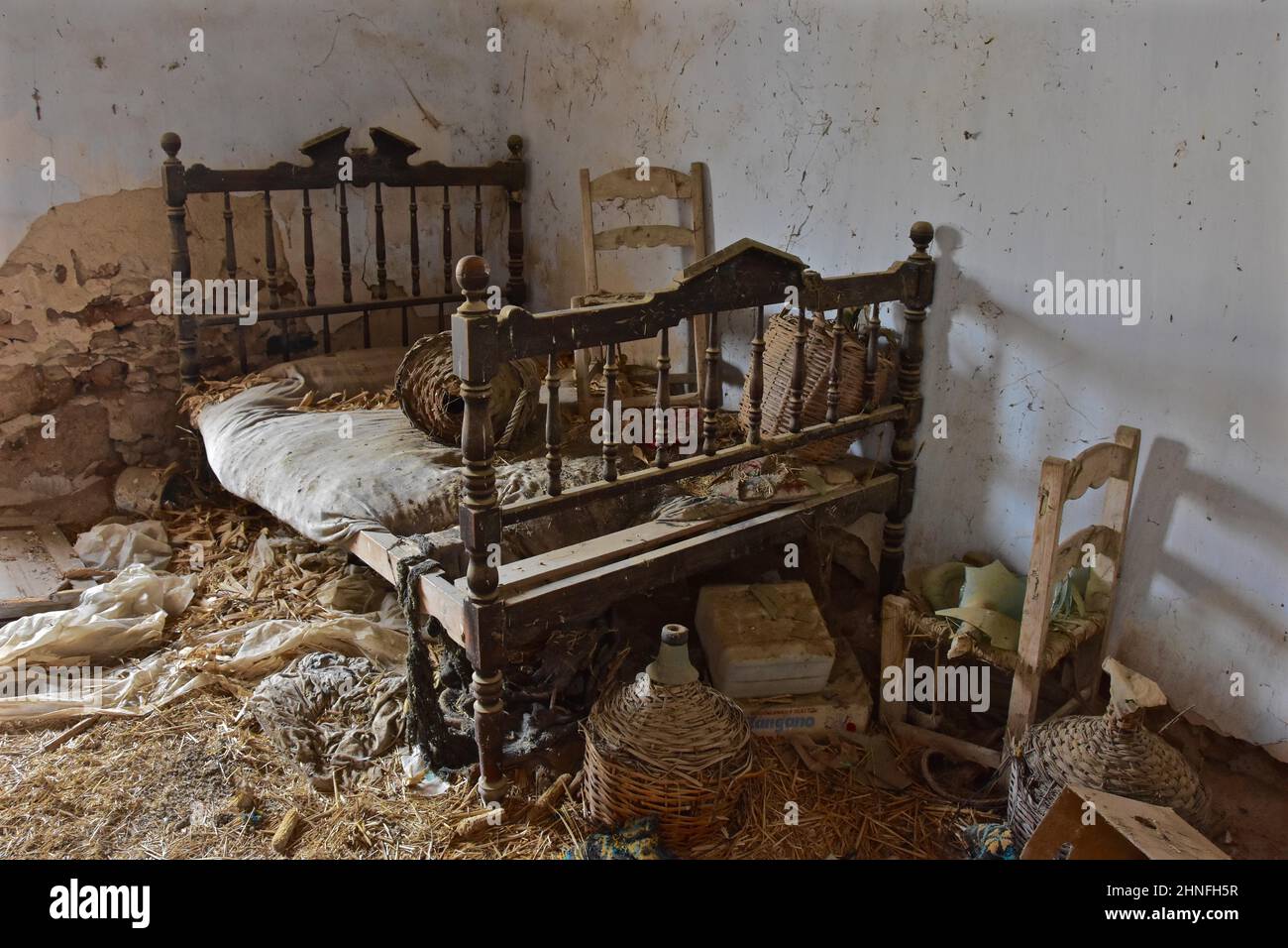 Holz-Ehebett mit Stuhl und Weinflaschen in Körben im verlassenen Haus, Chaos, Vandalismus, Bett, Ehebett, Doppelbett, Einzelbett Stockfoto