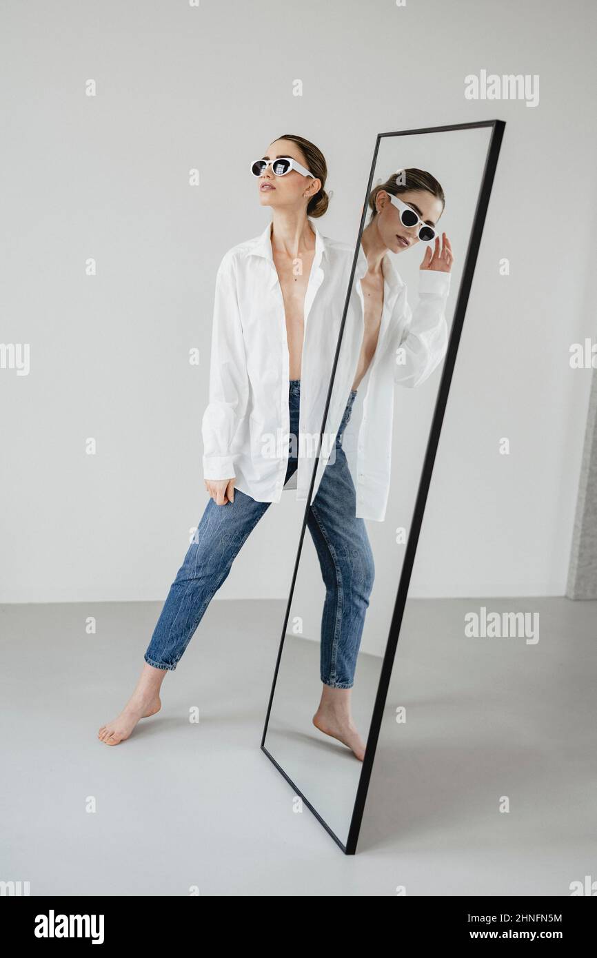 Attraktive junge Frau spiegelt sich in einem körpereigenen Spiegel wider Stockfoto