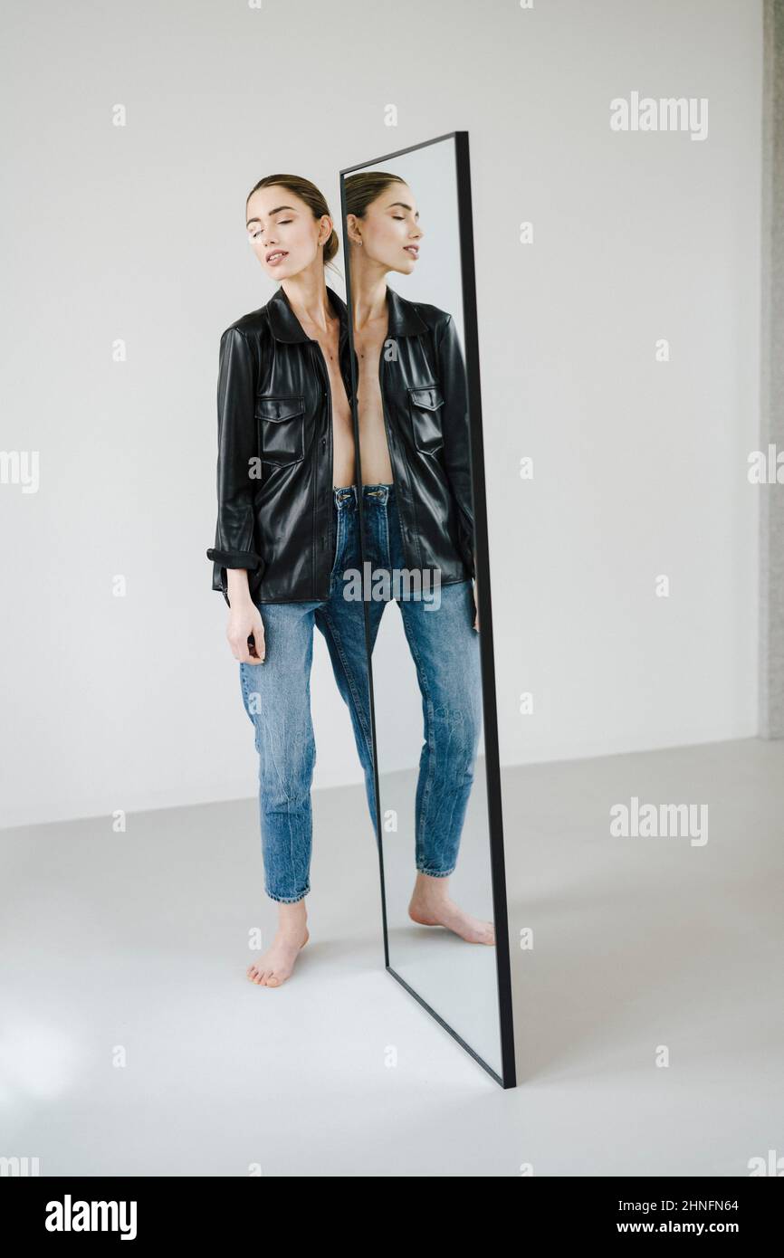 Attraktive junge Frau spiegelt sich in einem körpereigenen Spiegel wider Stockfoto