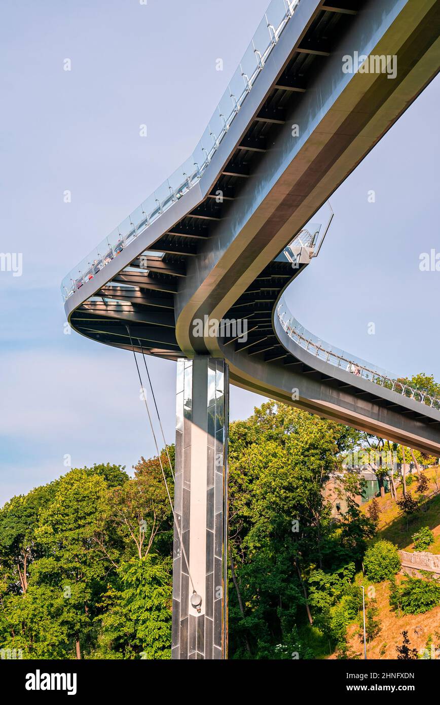 Fahrrad- und Fußgängerbrücke, die die grünen Hügel mit dem bewölkten Himmel verbindet Stockfoto