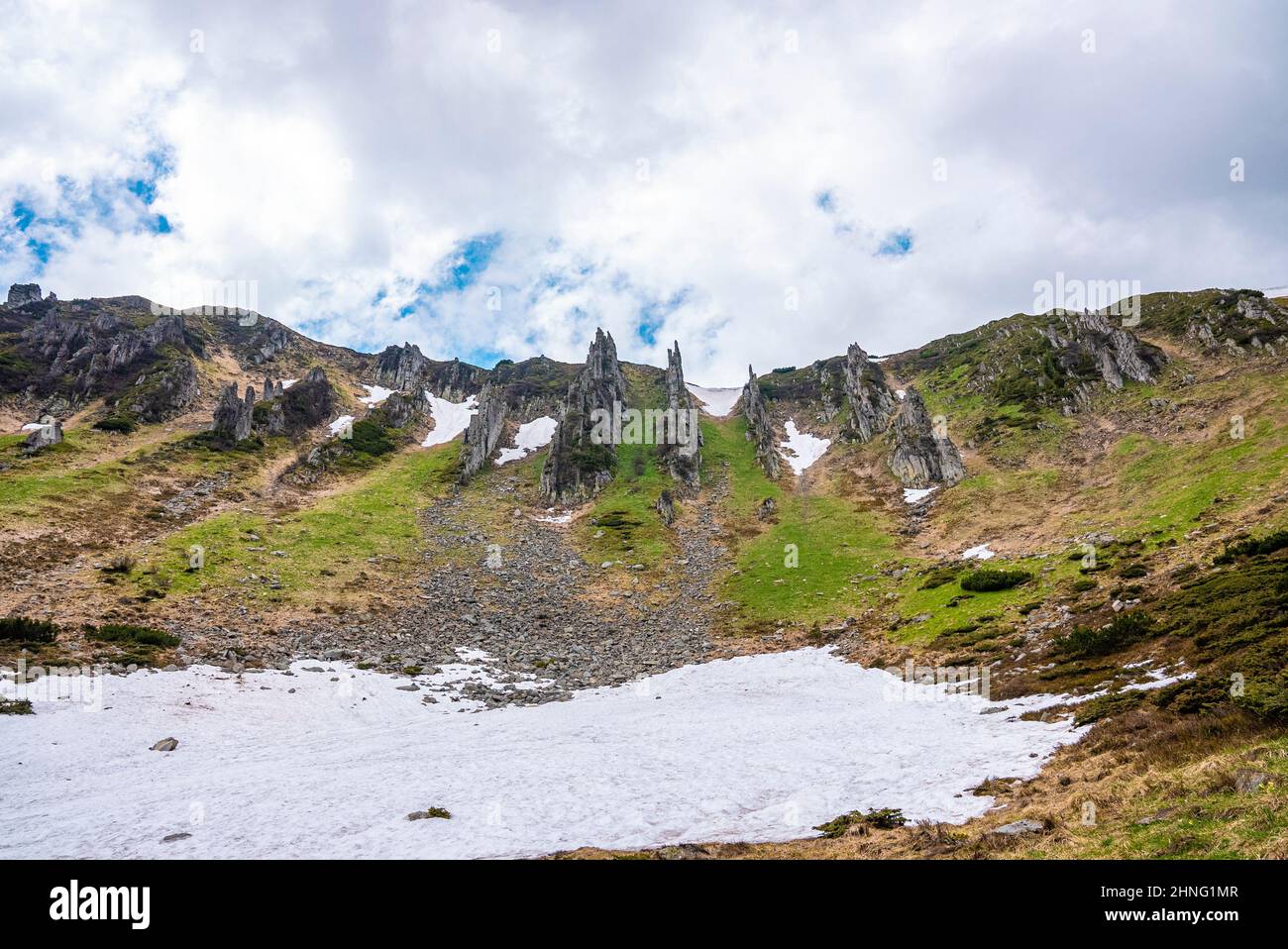 Blick auf gefrorenen schneebedeckten Hang des Hügels gegen felsige Klippen Stockfoto