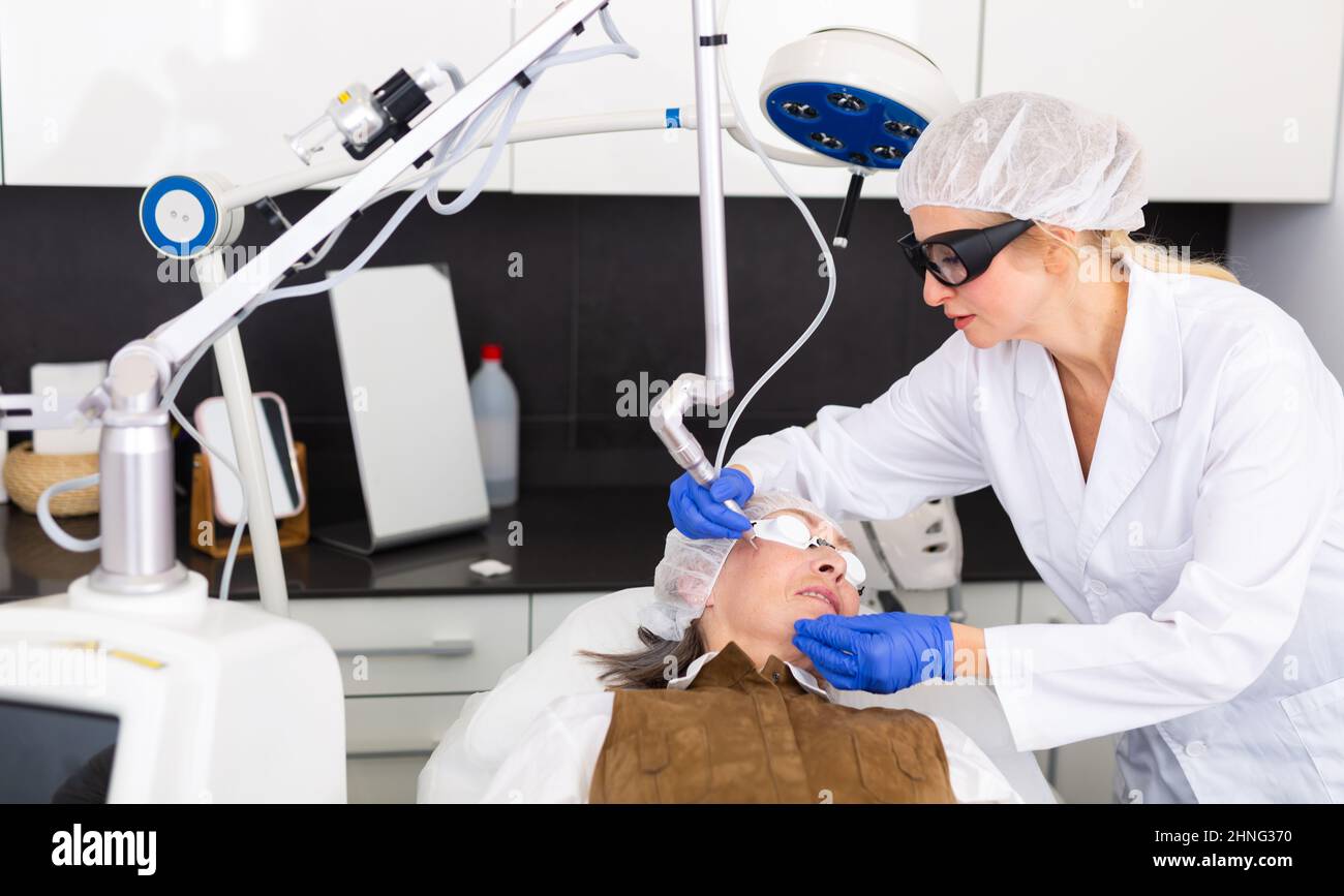 Kosmetologe tun Laser Warze Entfernung Verfahren für ältere Frau Stockfoto