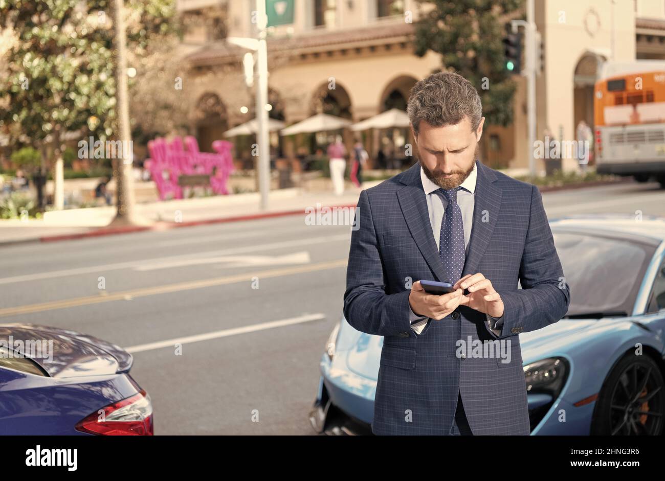 Selbstbewusste Manager mieten online. Schöner Geschäftsmann chatten auf dem Smartphone Stockfoto