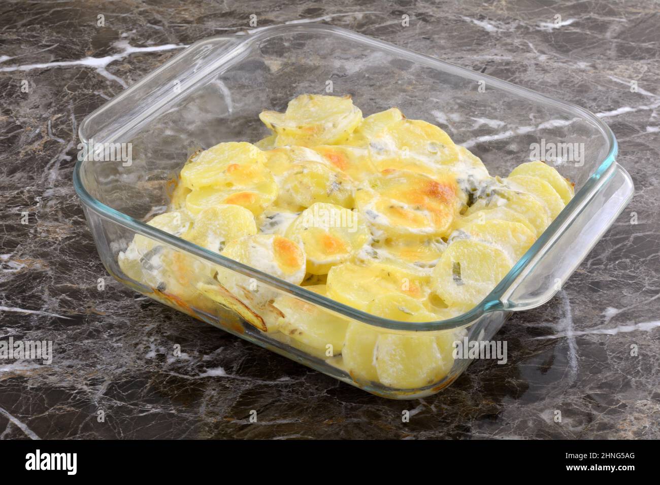 Gebackene Kartoffeln und Käse Auflauf in Glas Backform auf dem Tisch Stockfoto