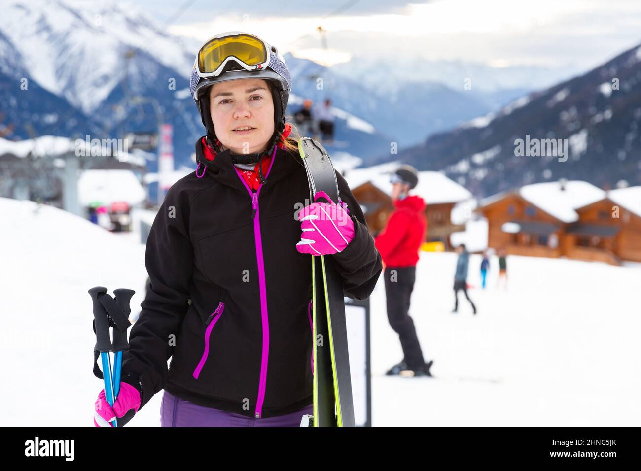 Frau in Skiausrüstung steht im Freien mit verschneiten Bergen im Hintergrund Stockfoto