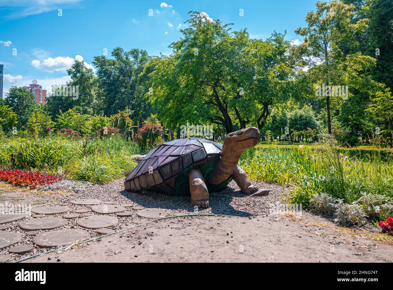 Hölzerne Schildkrötenskulptur neben dem Gehweg im Garten an sonnigen Tagen Stockfoto