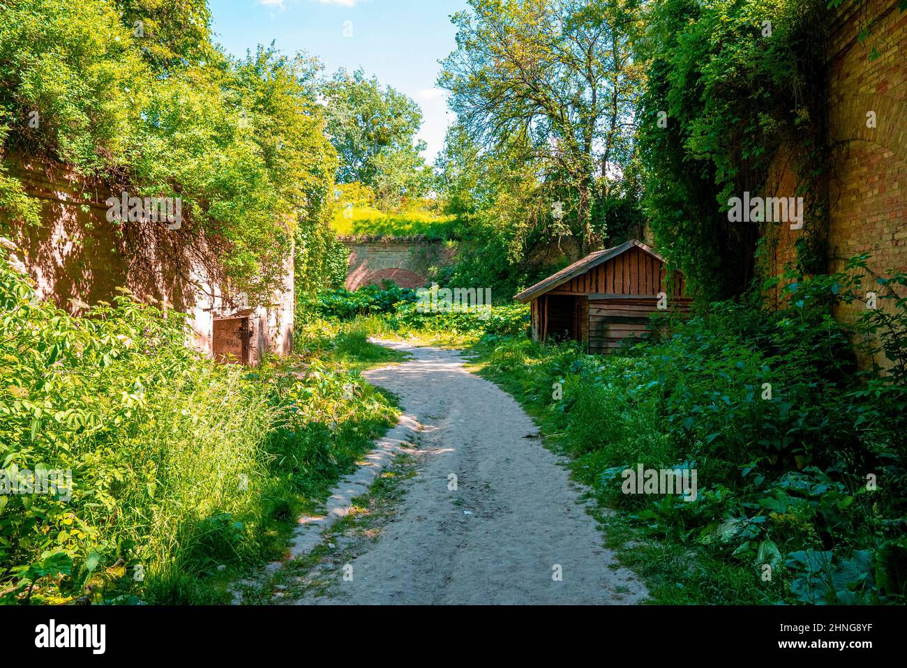 Fußweg durch alte verlassene Festung, umgeben von grünen Pflanzen an sonnigen Tagen Stockfoto