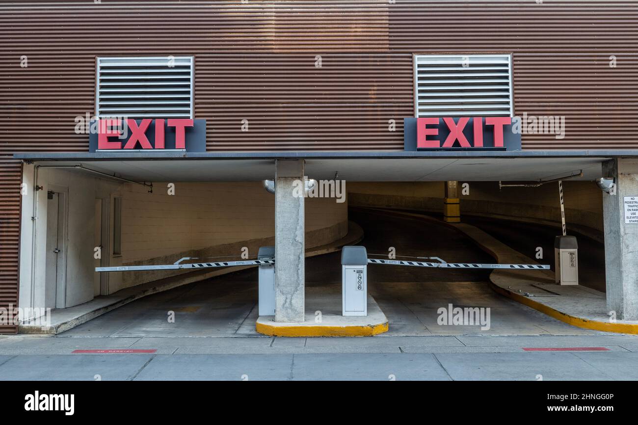 Zwei Rampen für die Parkgarage mit roten Ausstiegsschildern über Türen, an denen Autos das Gebäude verlassen. Stockfoto