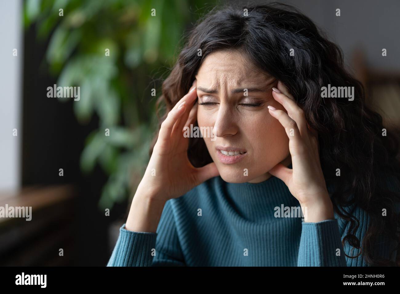 Ermüdete überarbeitete junge Frau, die an Migräne litt und sich um persönliche Probleme sorgte Stockfoto