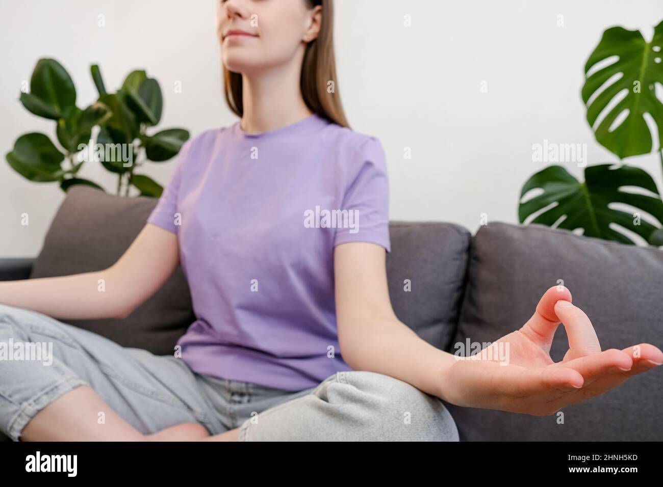 Psychiatrisches Versorgungskonzept. Selektivfokus einer jungen Frau, die mit gekreuzten Fingern, Harmonie und ohne Stress auf der Couch sitzt Stockfoto