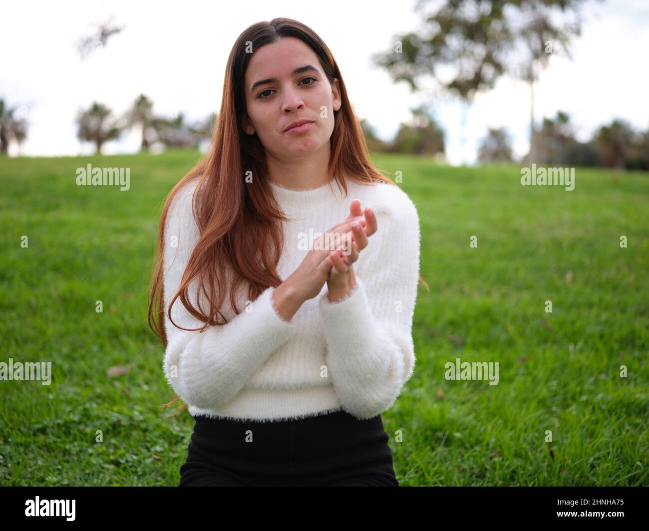 Eine junge Frau im Park klatschte herablassend zur Kamera. Stockfoto