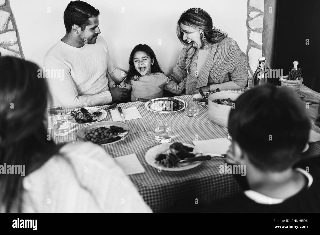 Lateinische Mutter und Vater haben Spaß mit ihrer Tochter während des Abendessen zu Hause - Fokus auf Kindergesicht - Schwarz-Weiß-Schnitt Stockfoto