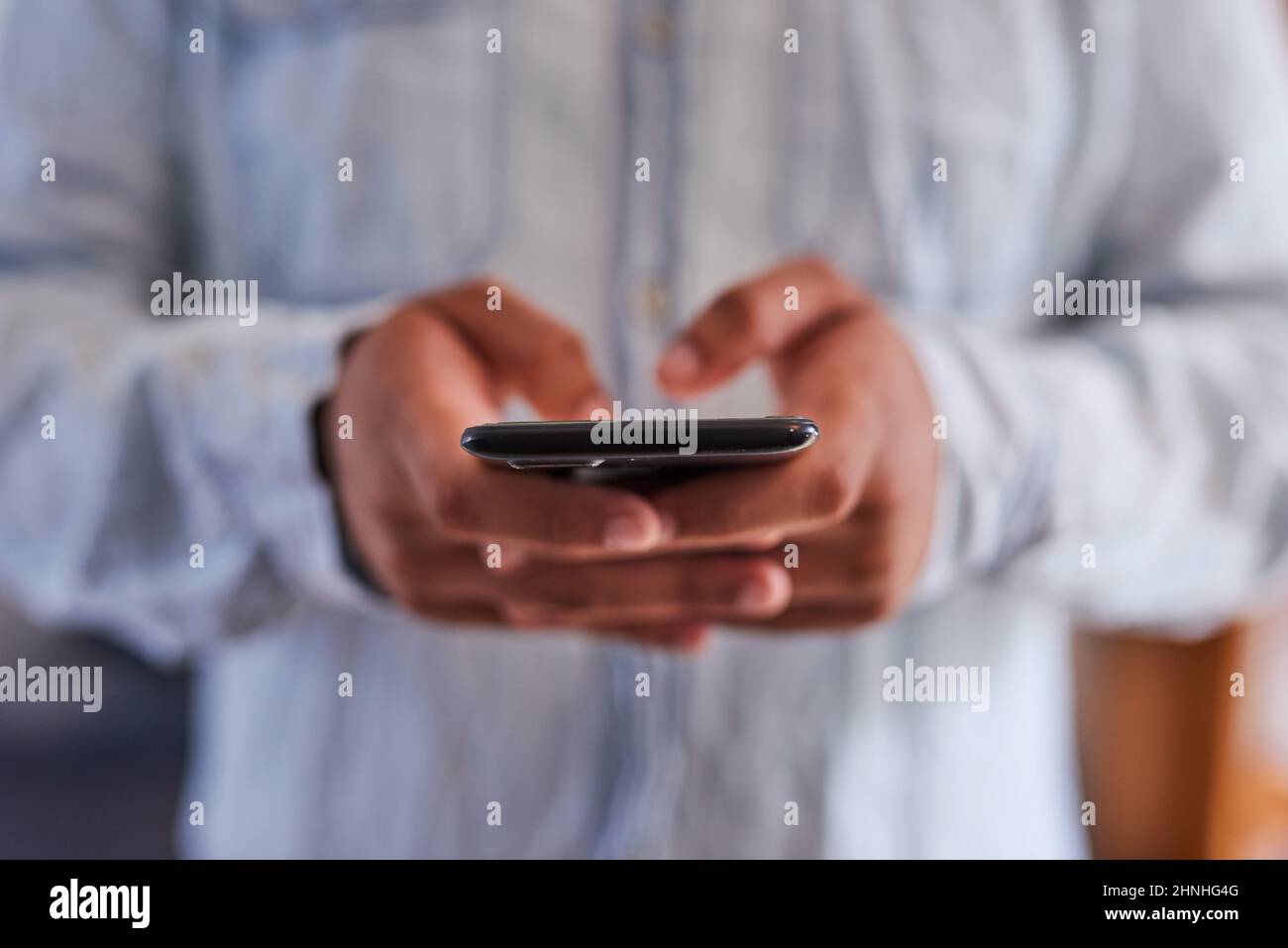 Eine enge Aufnahme der Hände eines Mannes, der auf einem Mobiltelefon tippt Stockfoto