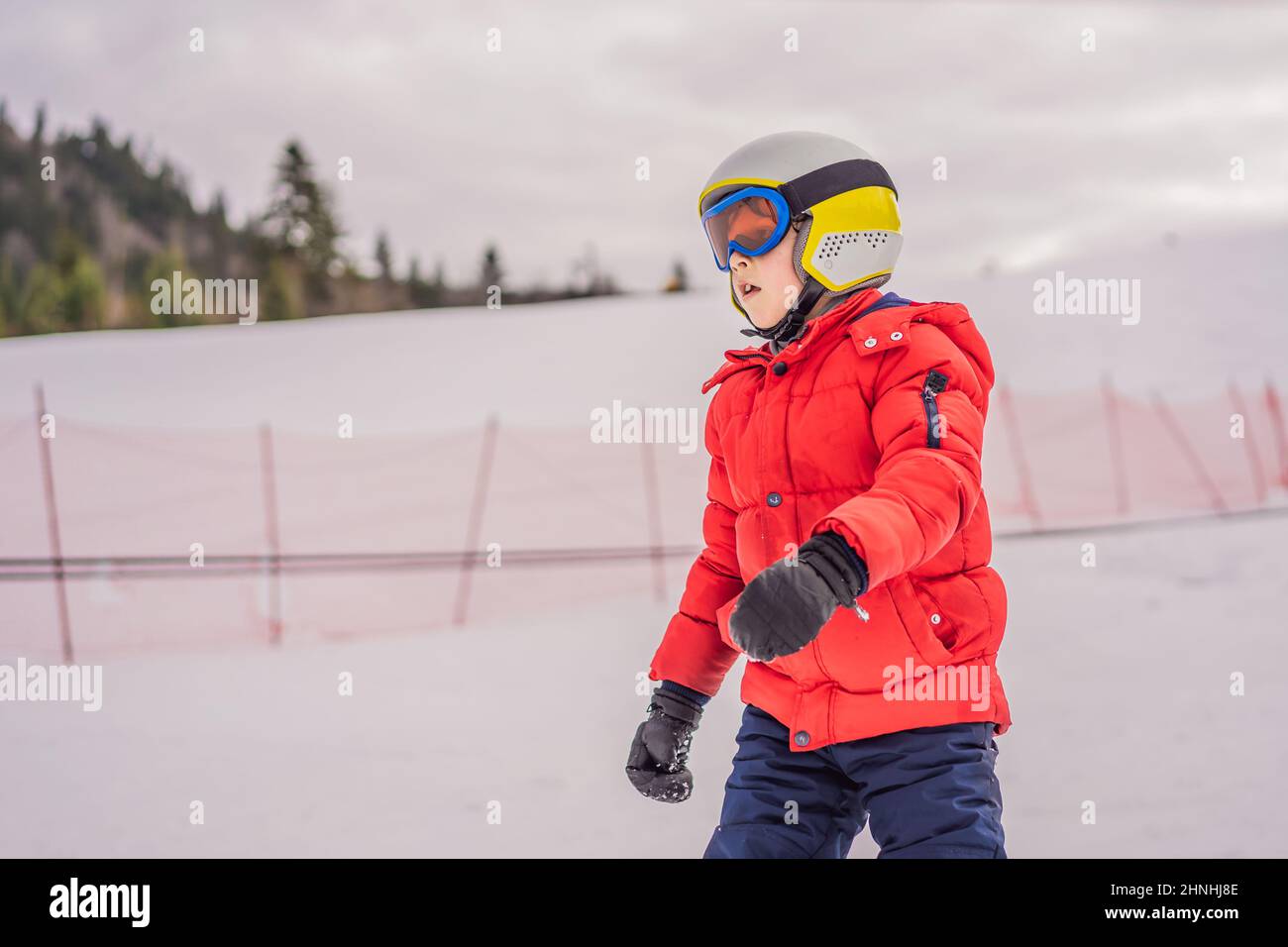 Kinder Skifahren in den Bergen. Aktives Kleinkind mit Schutzhelm, Schutzbrille und Stöcken. Skirennen für kleine Kinder. Wintersport für die ganze Familie. Kinder Ski Stockfoto