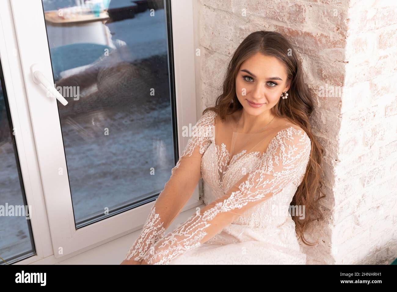 Braut mit fließendem Haar auf der Fensterbank. Hochwertige Fotos Stockfoto