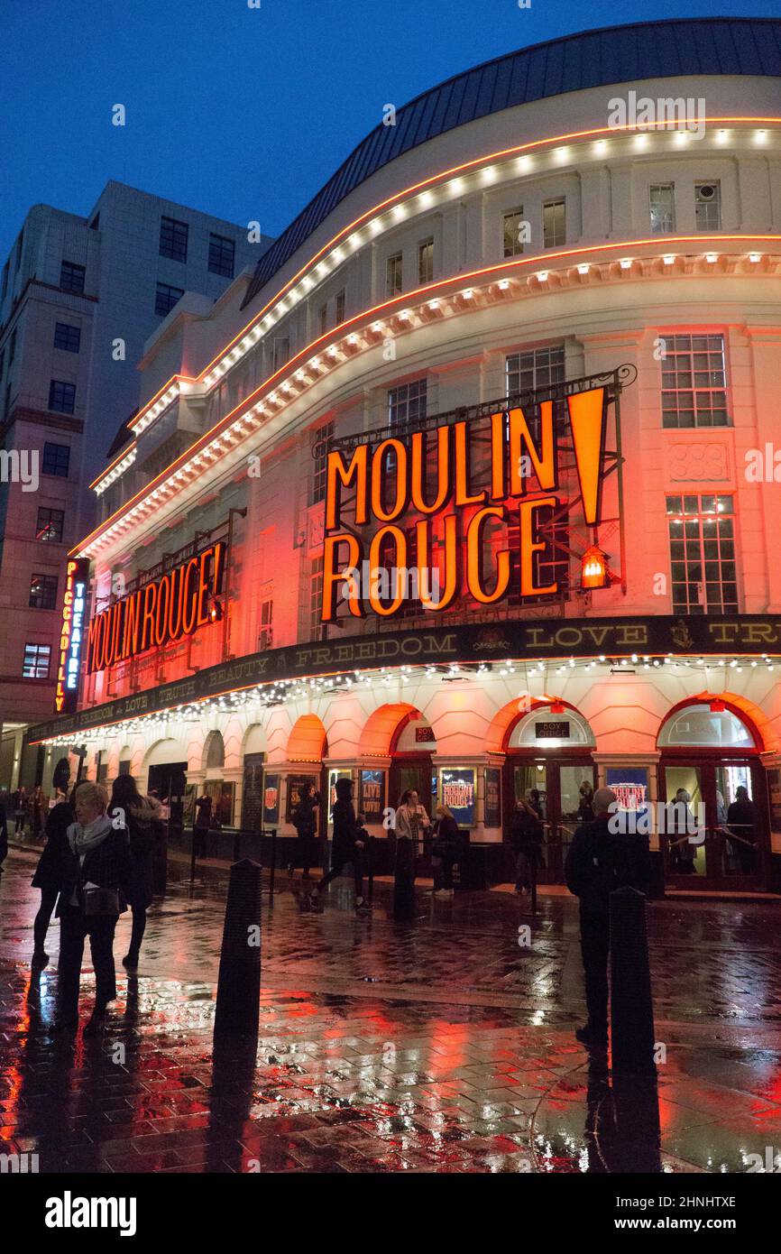 London, Großbritannien, 16. Februar 2022: Das Piccadilly Theatre in Soho wird für die Musikshow Moulin Rouge beleuchtet! Und die roten Lichter spiegeln sich an einem regnerischen Abend von nassen Straßen ab. Da sich die lockeren Einschränkungen in England lockerten, war das West End auf Halbzeit geschäftiger als lange Zeit, und der Gastgewerbe- und Kunstsektor profitiert von der Erholung. Anna Watson/Alamy Live News Stockfoto