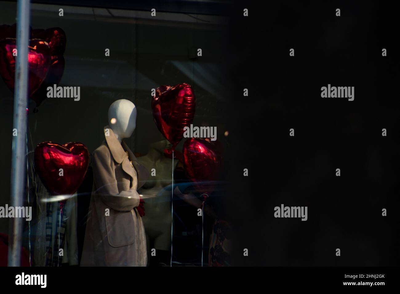 Rote Herzballons auf einem Schaufenster, um den Valentinstag mit einer Schaufensterpuppe zu feiern. Romantischer Tag der Liebe. Hochwertige Fotos Stockfoto