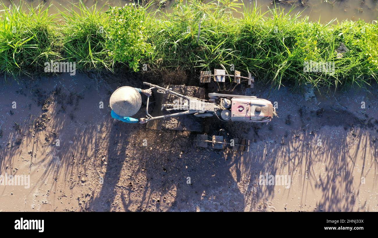 tod Blick auf undefinierten indonesischen Landwirt arbeiten mit Traktor auf einem Reisfeld. Luftdrohne geschossen Stockfoto