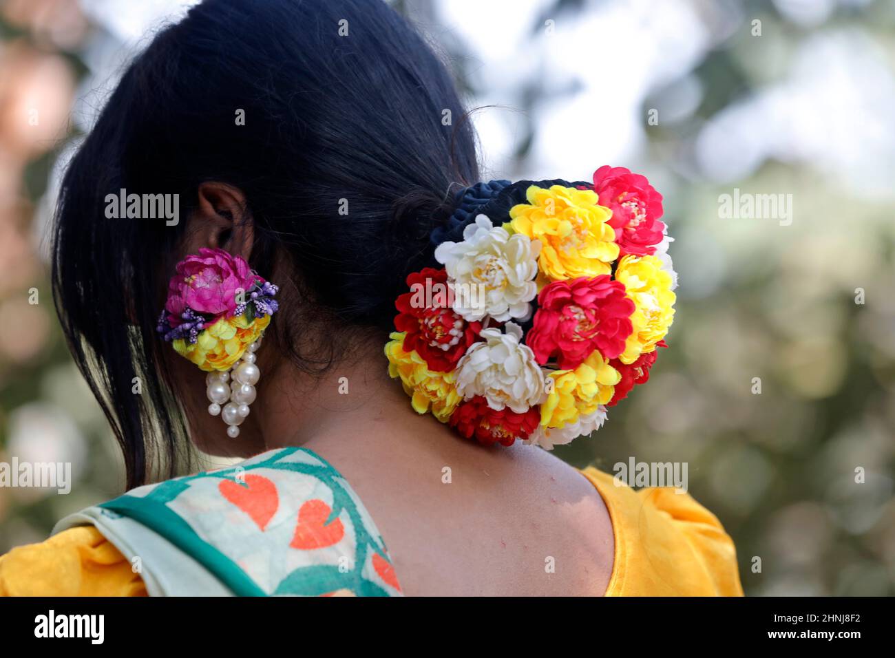 Dhaka, Bangladesch - 14. Februar 2022: Mädchen aus Bangladesch, die mit frühlingshaften Blumen auf ihren Haaren durch den Park läuft. Stockfoto