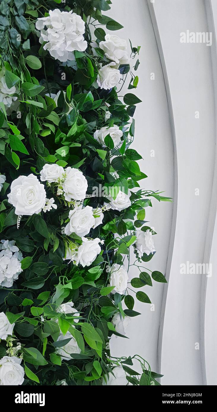 Ein Strauch aus europäischen Blumen kombiniert mit Rosen und Hortensien in einem Raum gegen eine weiße dekorative Wand. Stockfoto