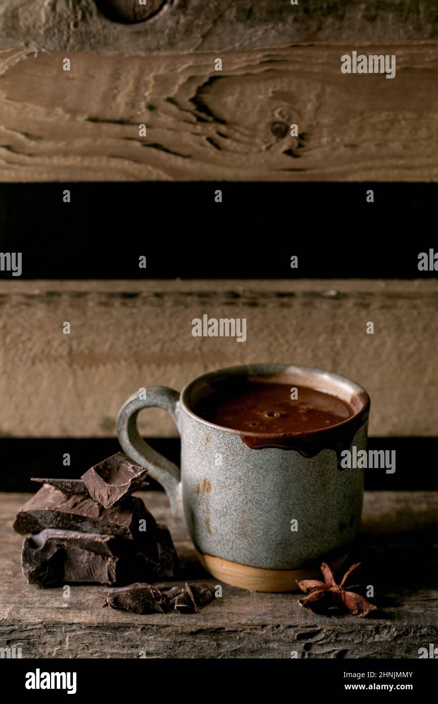 Tasse heiße würzige hausgemachte Schokolade Winter Drink mit gehackten dunklen Schokolade Bar auf alten Holzregal. Warmes, gemütliches Getränk. Stockfoto