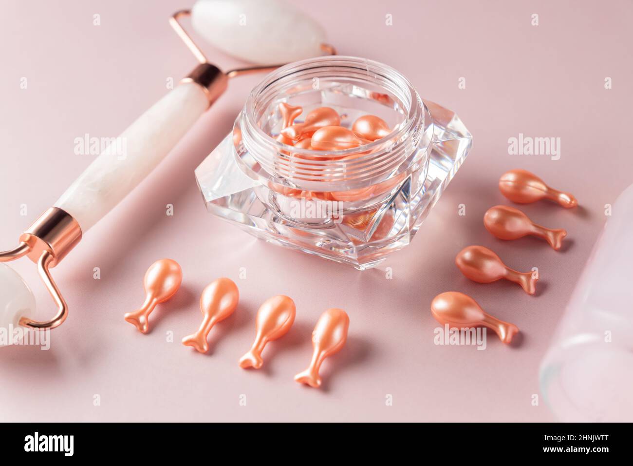 Pink Quarts Gesichtswalze und Serumkapseln mit Einzeldosis in einer Packung. Gesichtsmassage. Behandlung von Naturkosmetik. Monochromatischer Look, Knollenkonzept Stockfoto