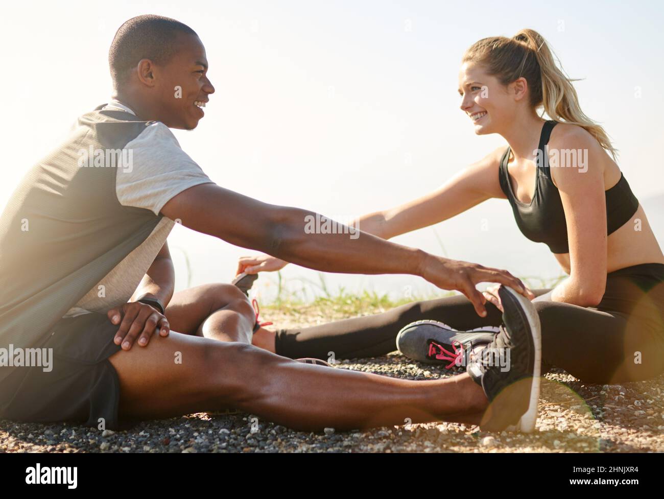 Partner auf und limbre oben. Aufnahme eines jungen frauen Paares, das sich vor einem Lauf im Freien dehnt. Stockfoto