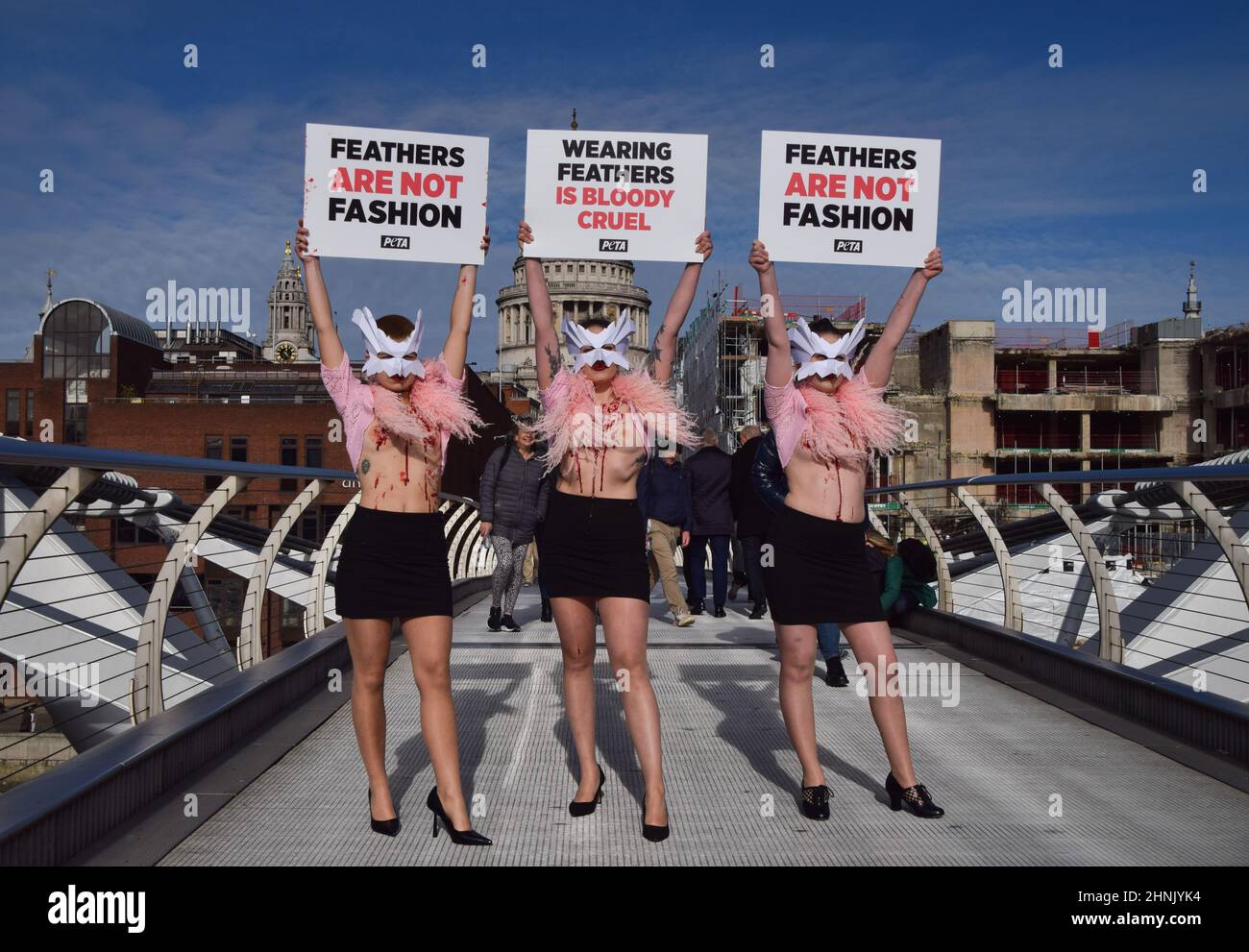 London, Großbritannien. 17th. Februar 2022. PETA-Aktivisten mit Vogelmasken und freigelegten „blutigen und gerupften“ Truhen inszenierten auf der Millennium Bridge einen „Laufsteg“, um gegen den Einsatz von Vogelfedern in Kleidungsstücken und Accessoires auf der London Fashion Week zu protestieren. Kredit: Vuk Valcic/Alamy Live Nachrichten Stockfoto